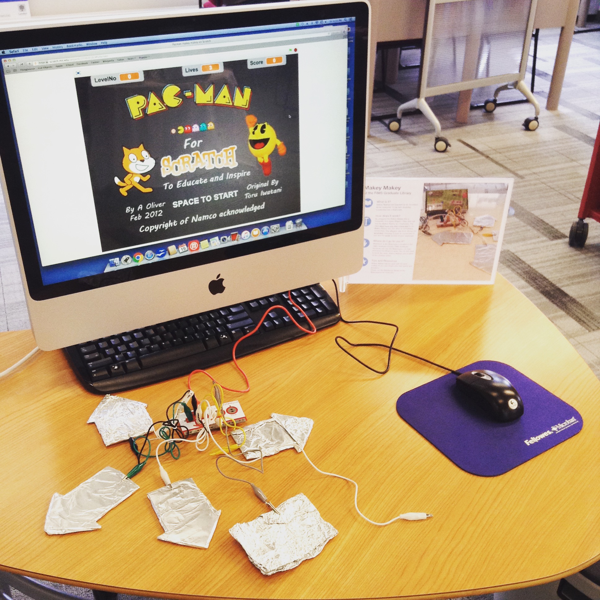 computer with image of pac man on it and large arrow keys made from tin foil on desk