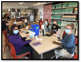 A group of students holding up the books they finished binding in the FIMS Graduate Library. 