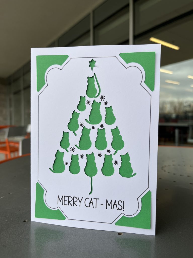 Green and white card featuring a christmas tree made of cat shapes, and the text, "Merry Cat-Mas!"