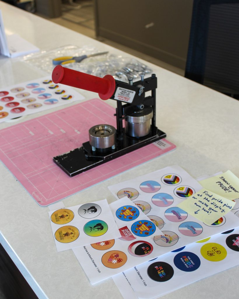 The button maker at the library's maker space with the templates to make pride pins.